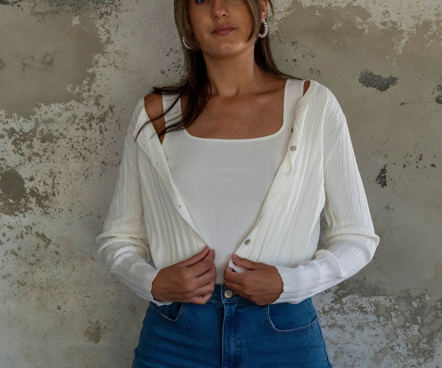 Gilet cardigan blanc porté avec un top blanc et une jupe en jean