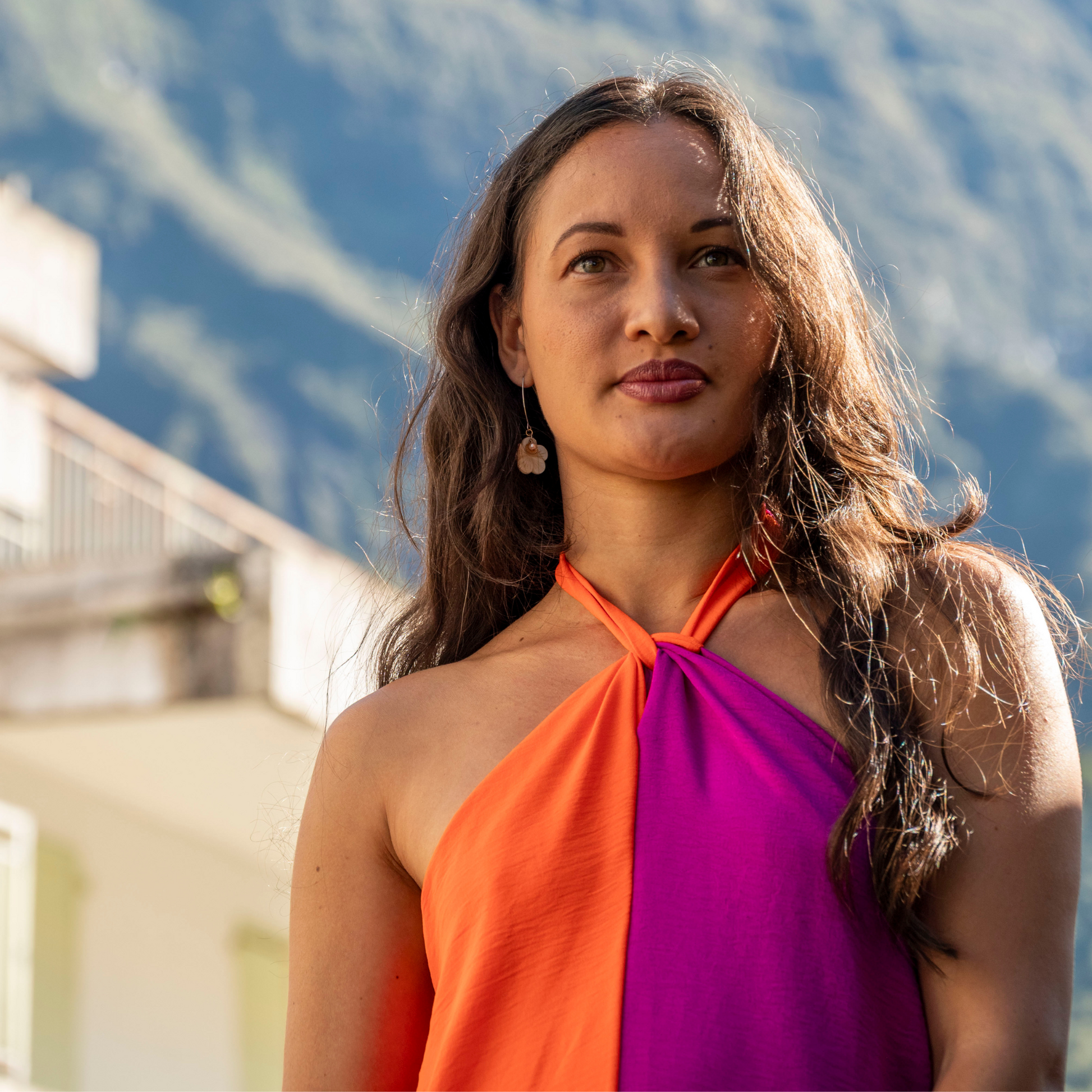 Femme regardant au loin portant robe longue bicolore mauve et orange encolure américaine